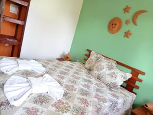 1 cama con edredón y almohadas en un dormitorio en Pousada Coruja Branca, en Berlinque