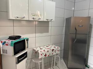 uma cozinha com um micro-ondas, uma mesa e um frigorífico em Apartamento área central em Ubatuba