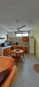 eine Küche mit einem Tisch und Stühlen sowie einem Kühlschrank in der Unterkunft Busy Bee Apartments in Kololi