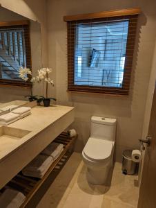 a bathroom with a toilet and a sink and a window at Hacienda Samana Bay Hotel in Santa Bárbara de Samaná