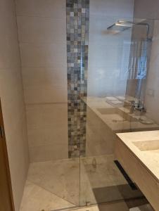 a shower with a glass door next to a sink at Hacienda Samana Bay Hotel in Santa Bárbara de Samaná