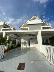 un grand bâtiment blanc avec un parking dans l'établissement Teratak Persona Homestay. 4 rooms double storey terrace in Kuantan City., à Kuantan