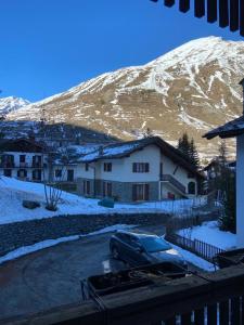 un coche aparcado frente a una casa con una montaña cubierta de nieve en Le chalet du skieur en La Thuile