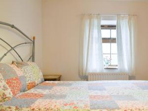 1 dormitorio con edredón en una cama con ventana en Meadow Lodge-e4105 en Aspatria