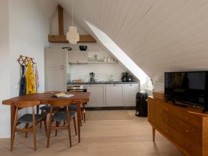 a kitchen and dining room with a table and a tv at Confort moderne à Sauzon avec vue sur port, accessible PMR, wifi, linge inclus - FR-1-418-184 in Sauzon