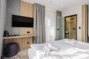 um quarto de hotel com uma cama e uma televisão de ecrã plano em Wielka Krokiew Residence&SPA - Zakopane - JACUZZI, SAUNA, TĘŻNIA SOLANKOWA, SPA, GRILL em Zakopane