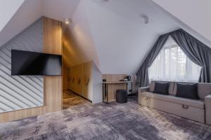 a living room with a couch and a tv at Wielka Krokiew Residence&SPA - Zakopane - JACUZZI, SAUNA, TĘŻNIA SOLANKOWA, SPA, GRILL in Zakopane