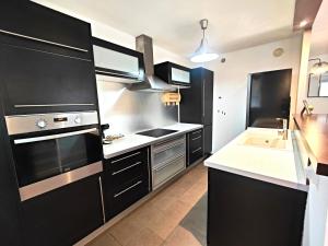 una cocina con armarios negros y fregadero en *Appart Lily* Parking* 5 min du cœur de ville, en Aubagne