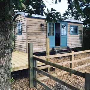 um pequeno chalé de madeira com um deque de madeira em Skylark Shepherds Hut em Bath