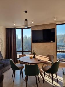 a living room with a table and chairs and a tv at Chillax Chalet in Yablunytsya