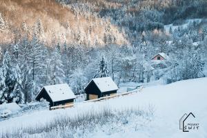 Projekt ŚWIT - domki z prywatną jacuzzi i sauną في شفينا: مجموعة من الكبائن في غابة مغطاة بالثلج