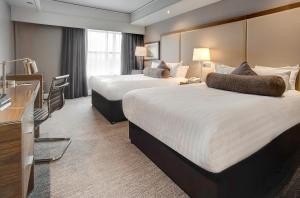 Habitación de hotel con 2 camas y escritorio en Sandman Signature London Gatwick Hotel, en Crawley