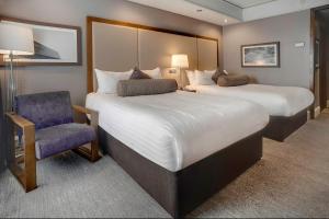 una habitación de hotel con 2 camas y una silla en Sandman Signature London Gatwick Hotel en Crawley