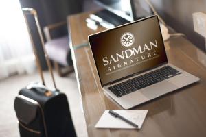 laptopa siedzącego na drewnianym stole w obiekcie Sandman Signature London Gatwick Hotel w mieście Crawley
