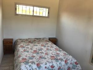 a bedroom with a bed with a floral bedspread and a window at India del mar II in Chapadmalal