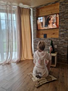 een jong meisje dat op de grond zit en televisie kijkt bij Homoljski pogled Banja Zdrelo in Ždrelo