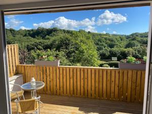 a patio with a table and chairs on a wooden deck at Sunny Nook, Pretty 1 bed modern cottage close to Woolacombe in Ilfracombe