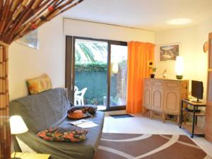 ein Wohnzimmer mit einem Sofa und einer Glasschiebetür in der Unterkunft Appartement Fréjus, 2 pièces, 4 personnes - FR-1-226A-56 in Fréjus