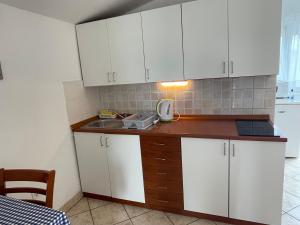 a kitchen with white cabinets and a sink at Apartments Zora in Nin