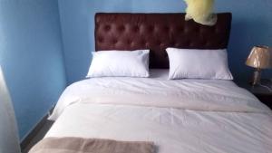 a bed with white sheets and a brown headboard and white pillows at Faigib Guest House in Chipata
