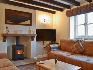 a living room with a couch and a fireplace at Dale End Cottage in Brassington