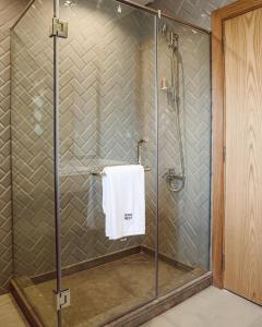 a shower with a glass door and a white towel at BIRD NEST at Sheikh Zayed in Sheikh Zayed
