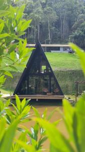 una casa con techo triangular sobre un río en Cabana A frame Paraíso nas Montanhas, en Marechal Floriano