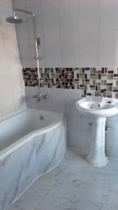 a bathroom with a white tub and a sink at Faigib Guest House in Chipata