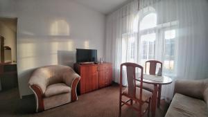 a living room with a tv and a chair and a table at Stella in Krynica Zdrój