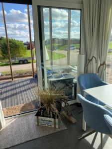 een kamer met een tafel, een blauwe stoel en een raam bij Seaside Beach House Chalet - Seeparx Süsel in Süsel