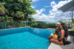 a group of people sitting next to a swimming pool at Karibea Squash Hôtel in Fort-de-France