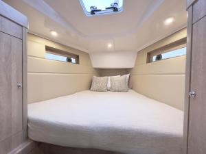- un lit dans une petite chambre avec 2 fenêtres dans l'établissement Hausboot Segelyacht Nui, à Burgtiefe auf Fehmarn 
