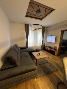 een woonkamer met een bank en een tafel bij Apartman Sara - DivčiNova in Divčibare