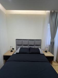 een slaapkamer met een groot zwart bed en 2 tafels bij Apartman Sara - DivčiNova in Divčibare