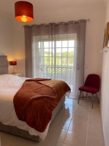 a bedroom with a bed and a red chair and a window at ALFELI-AP in Olhos de Água +28 photos