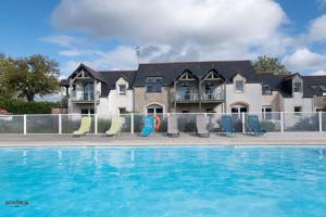 a swimming pool with chairs in front of a house at Apparthôtel Mont Saint Michel - Résidence Fleurdumont in Beauvoir