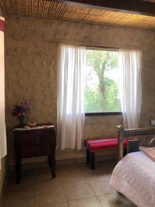 a bedroom with a window with a bench and a table at Matices de Molinos Hostal in Molinos