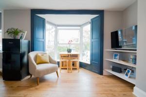een woonkamer met blauwe deuren en een stoel en een tafel bij Stunning 3 bed Home, 5 mins from Margate Beach in Kent