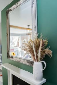 een spiegel en een vaas met een plant op een open haard bij Stunning 3 bed Home, 5 mins from Margate Beach in Kent