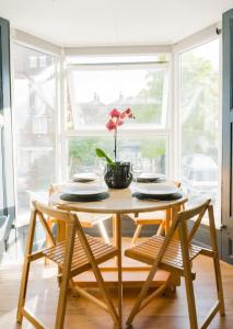 a table with chairs and a vase with a flower at Stunning 3 bed Home, 5 mins from Margate Beach in Kent