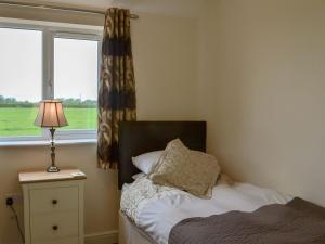 a bedroom with a bed with a lamp and a window at Roosters - E4864 in Chapel Saint Leonards