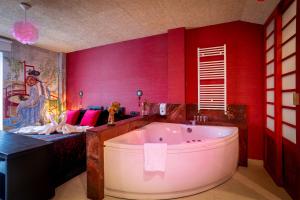 La salle de bains rouge est pourvue d'une grande baignoire et d'un lit. dans l'établissement Posada la Leyenda, à Santillana del Mar