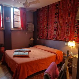 a bedroom with a bed with orange sheets and red curtains at La casa di Ciaccia in Camaiore