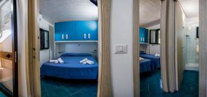 a room with two blue beds and a mirror at Villaggio Residence Pietra Grigia in Marina di Camerota