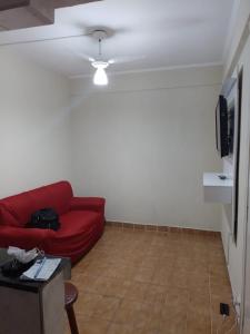 un salon avec un canapé rouge et une télévision dans l'établissement Coração da Ocian, à Praia Grande