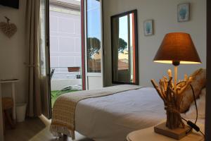 1 dormitorio con cama, lámpara y ventana en Hôtel La Villa des Oliviers, en Cagnes-sur-Mer
