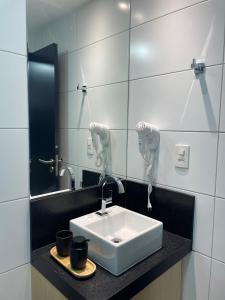 a bathroom with a white sink and a mirror at Flat Alto Padrão em Tambaú in João Pessoa