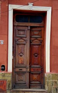 una puerta de madera en el lateral de un edificio rojo en Punto Salta Hostel en Salta