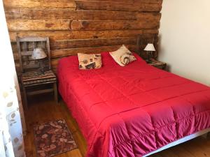 a bedroom with a red bed with a wooden wall at ALIWWE in Uspallata