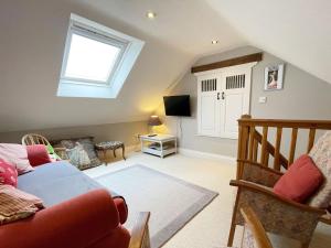 a living room with a red couch and a window at Le Jardin in Rodmarton